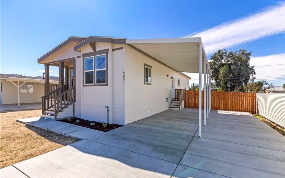 Cream manufactured home with a side carport and front steps