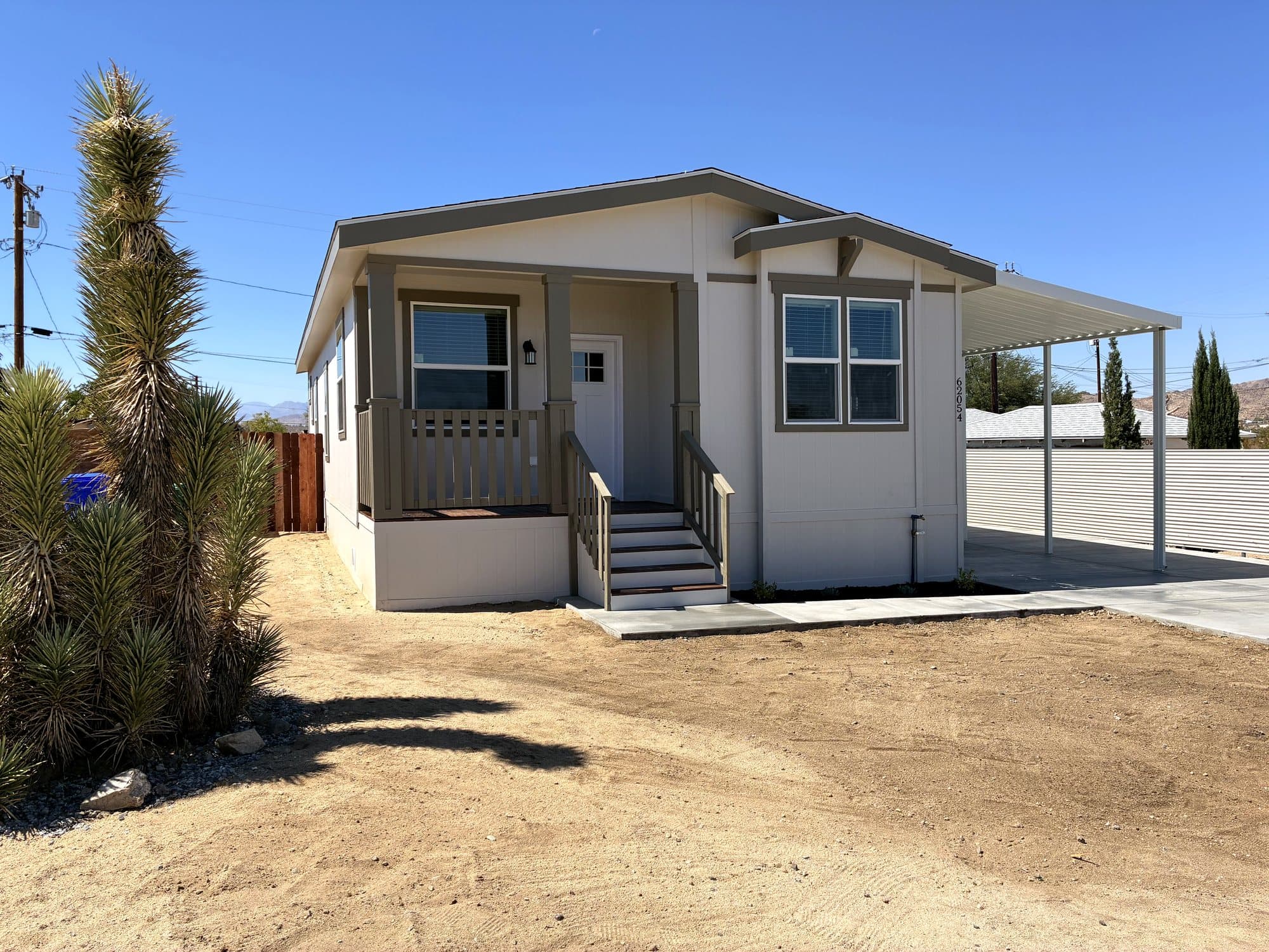 Cream manufactured home with a covered entry and carport in the desert